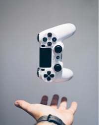a PS4 controller floating above a hand